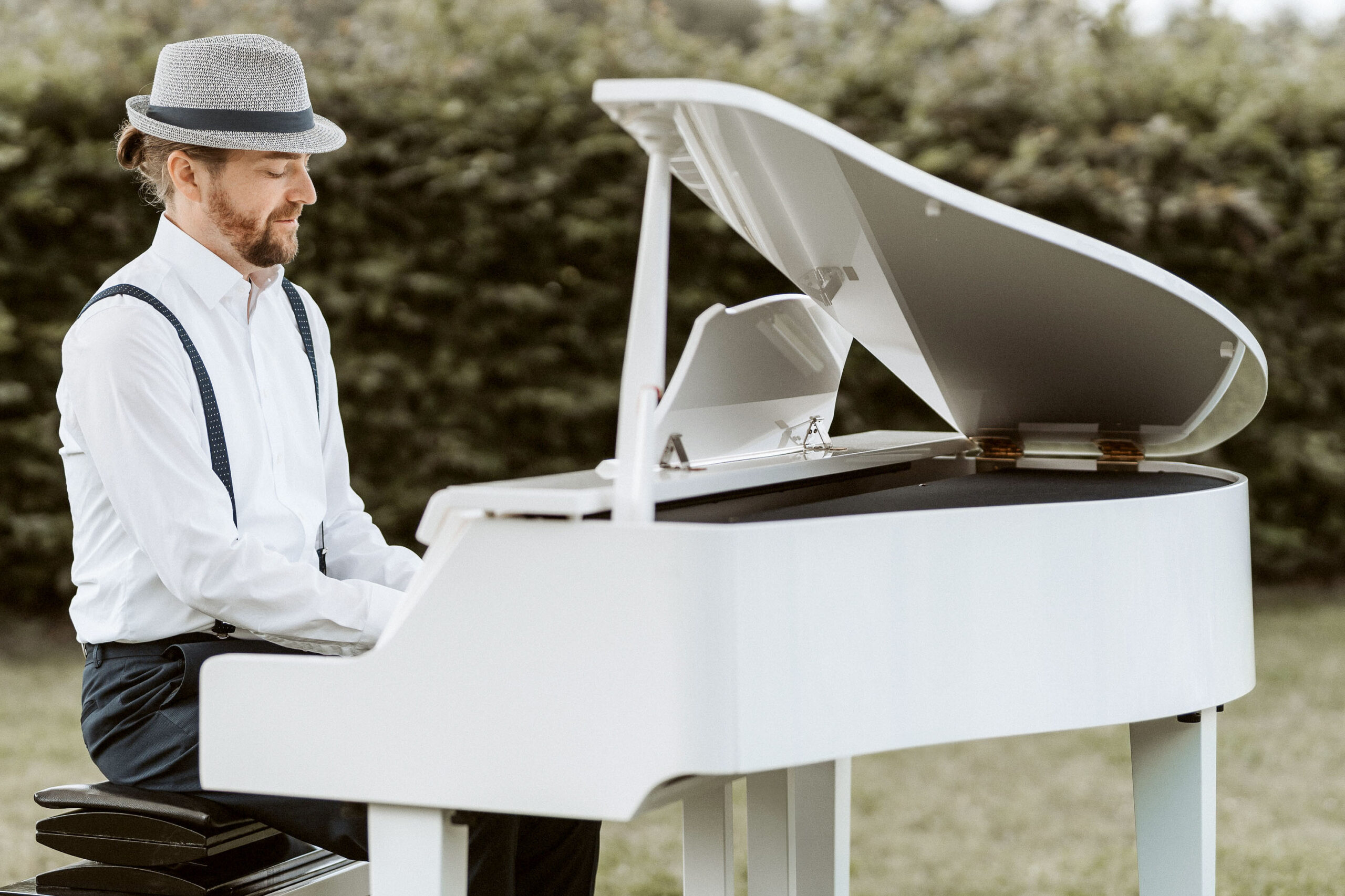 Claudio Lanz spielt auf seinem weißen Flügel im romantischen Garten während einer Trauung